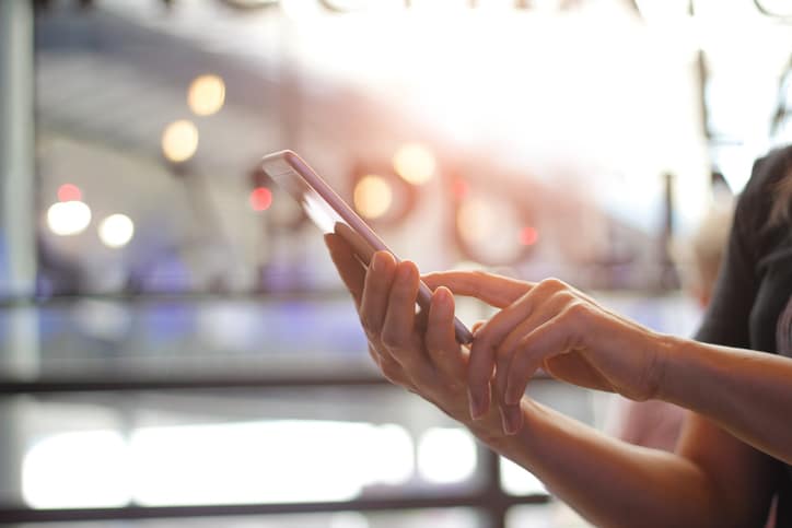 Close up of women's hands holding smartphone. Her watching sms, message, e-mail on mobile phone in coffee shop. Blurred background.